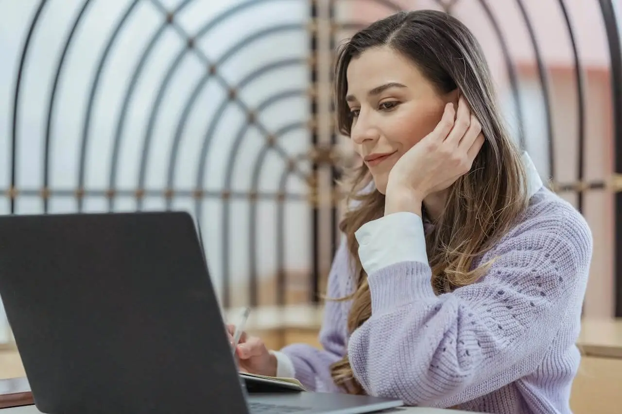 Positive woman working-on-laptop-and-writing-in-notebook Confident employee in charge of her own work