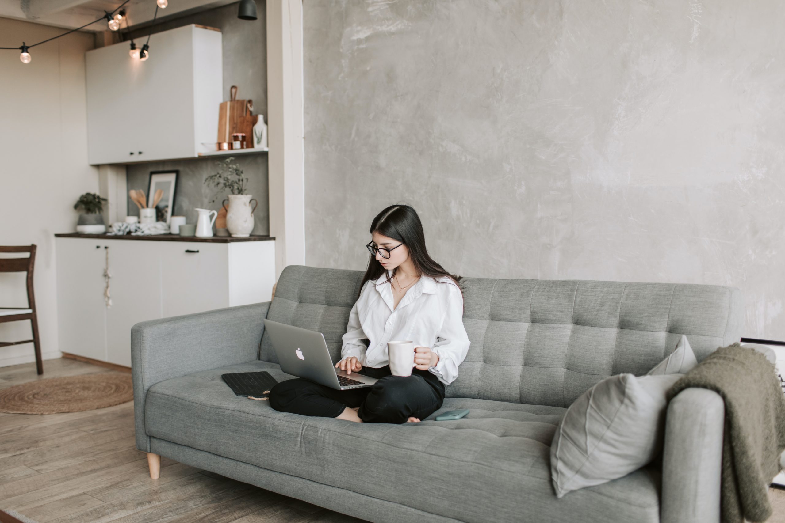 sitting-woman-couch-laptop Woman doing virtual onboarding while sitting on couch