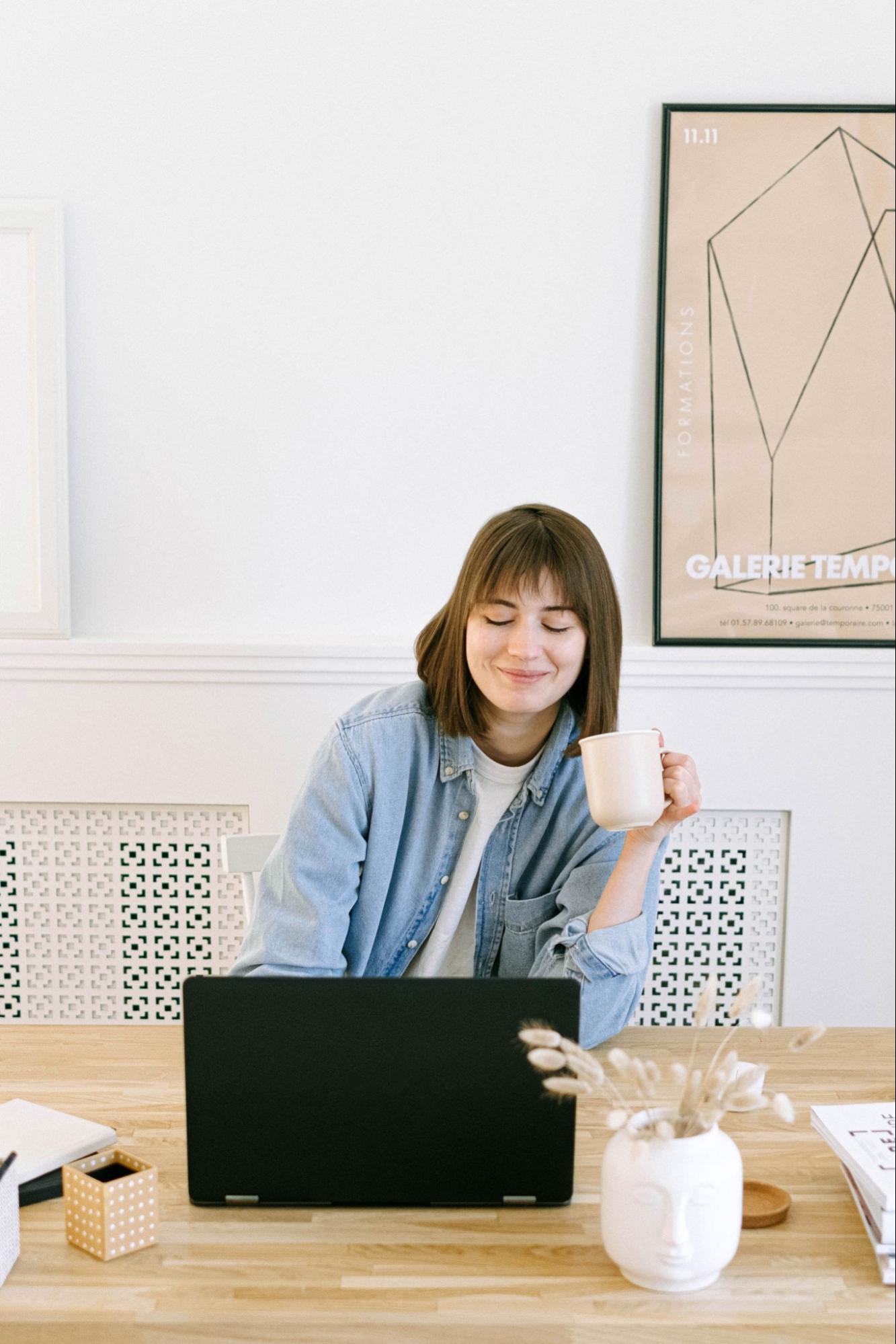 smiling-woman-with-mug-on-laptop Woman with mug doing one-on-on meeting on laptop