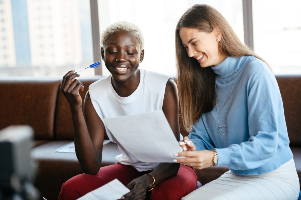 Two women colleagues reading performance review phrases