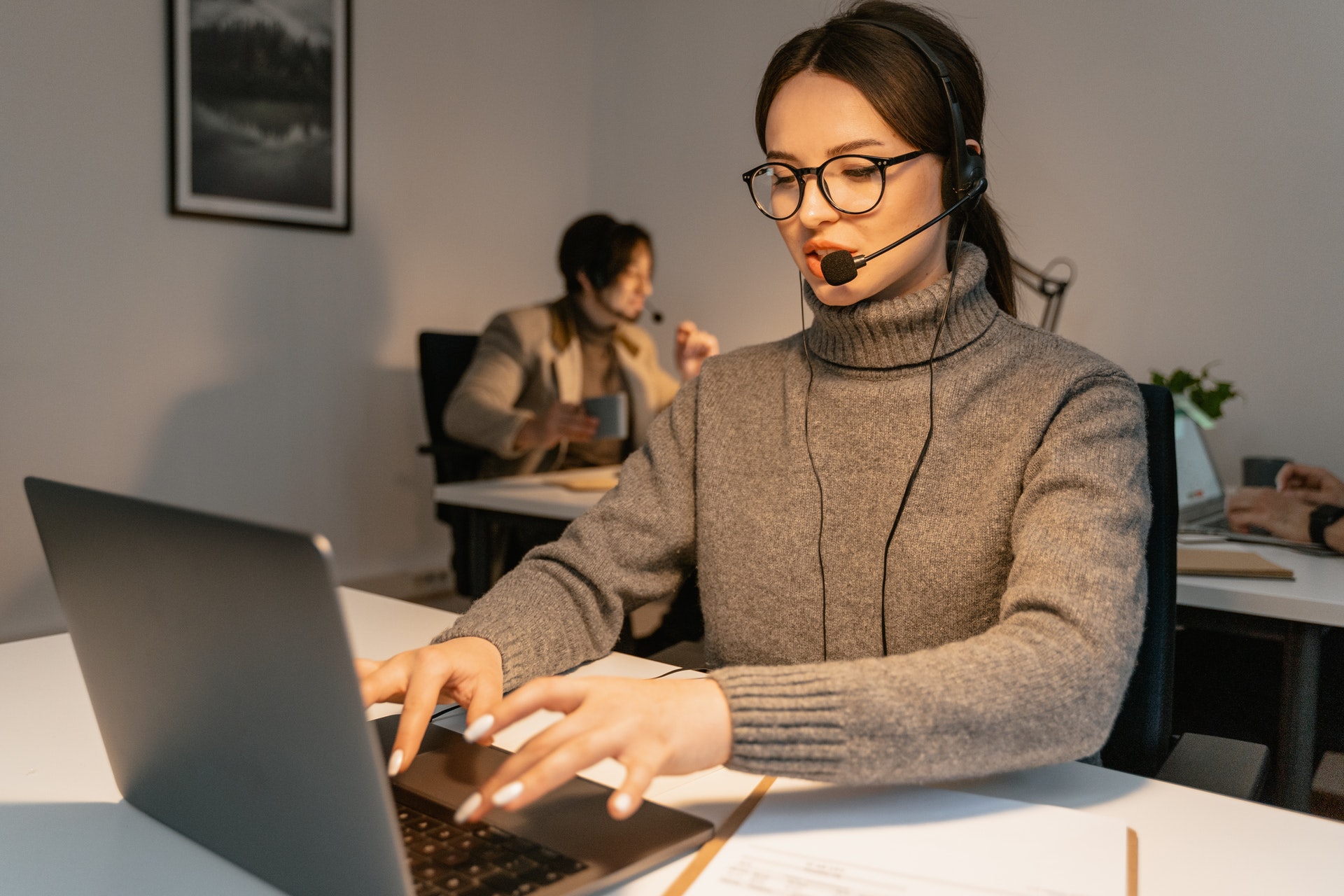 two-women-using-laptops-in-office Woman using laptop wearing headset discussing employee engagement ideas