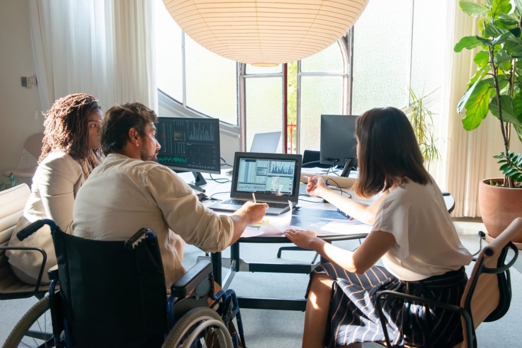 Three coworkers one in wheelchair discussing employee attrition