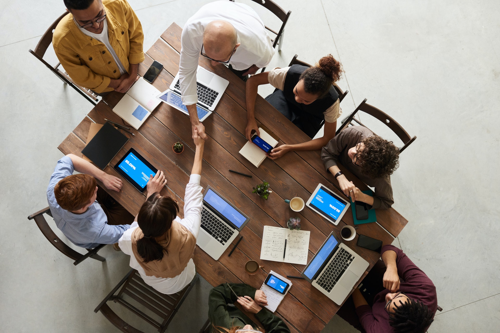 eight-people-at-desk-working Group of professionals at desk discussing onboarding survey questions