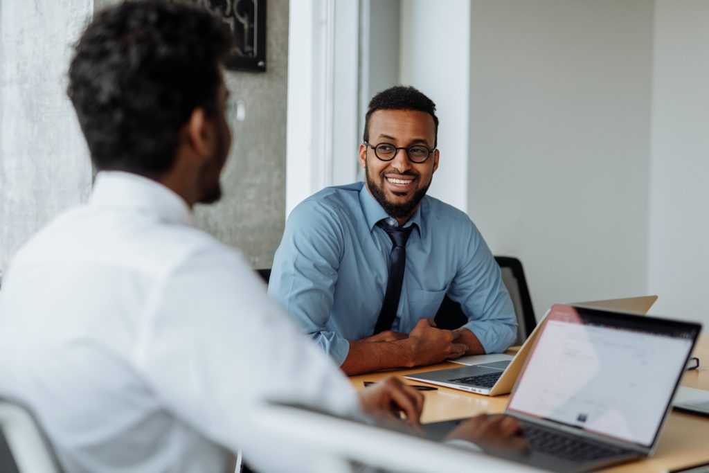 Two men of colour sitting facing each other smiling about organizational success