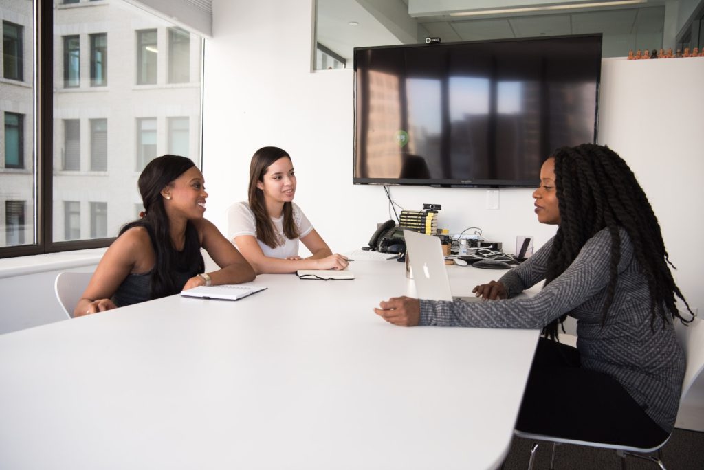 Three women of colour discussing delegation of authority in office
