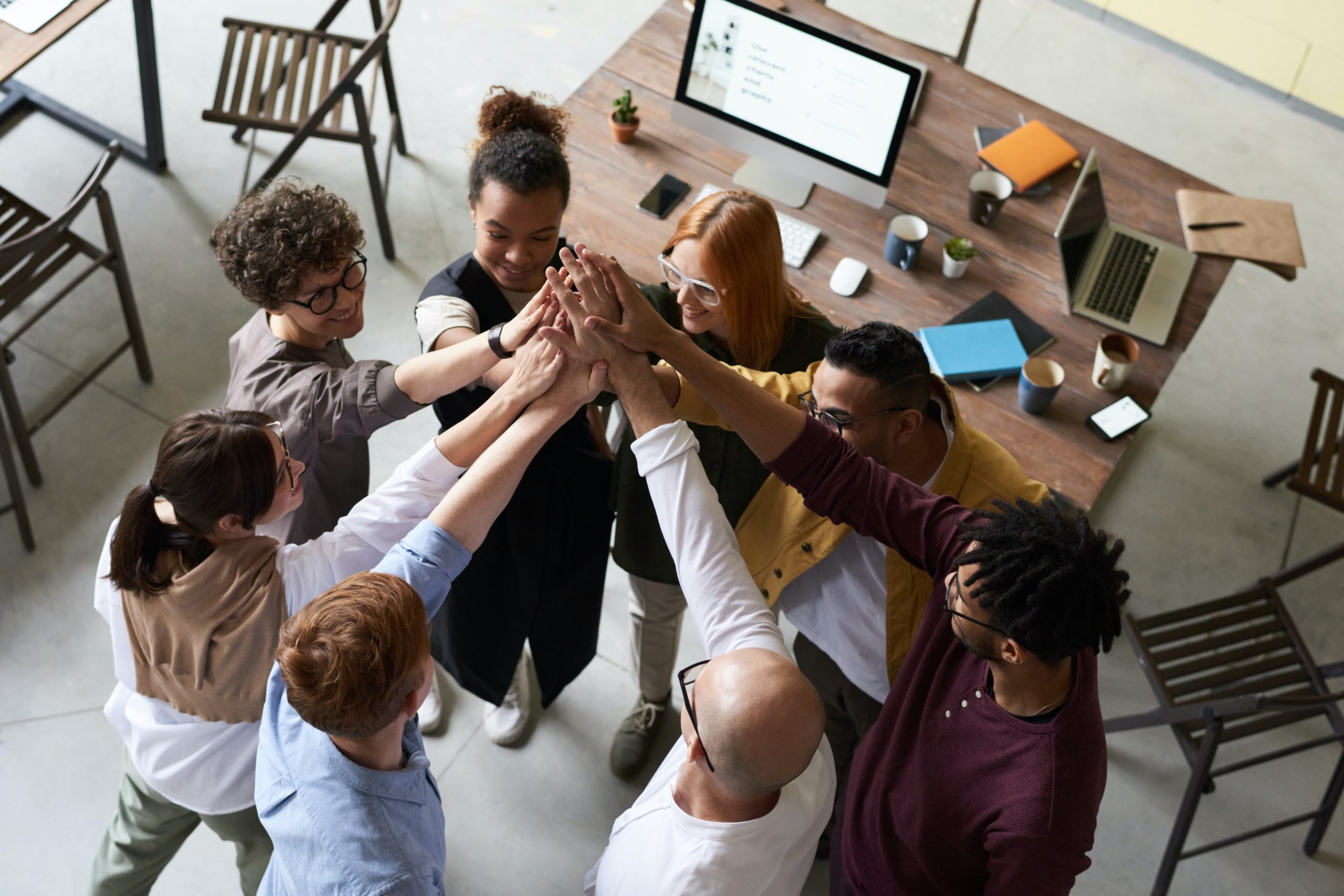people-hands-together-diverse Inclusive group of diverse colleagues celebrating after culture strategy meeting