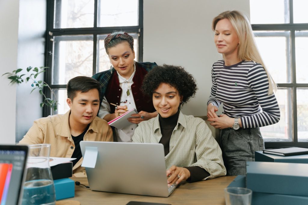 Four diverse colleagues reading about PTO on laptop