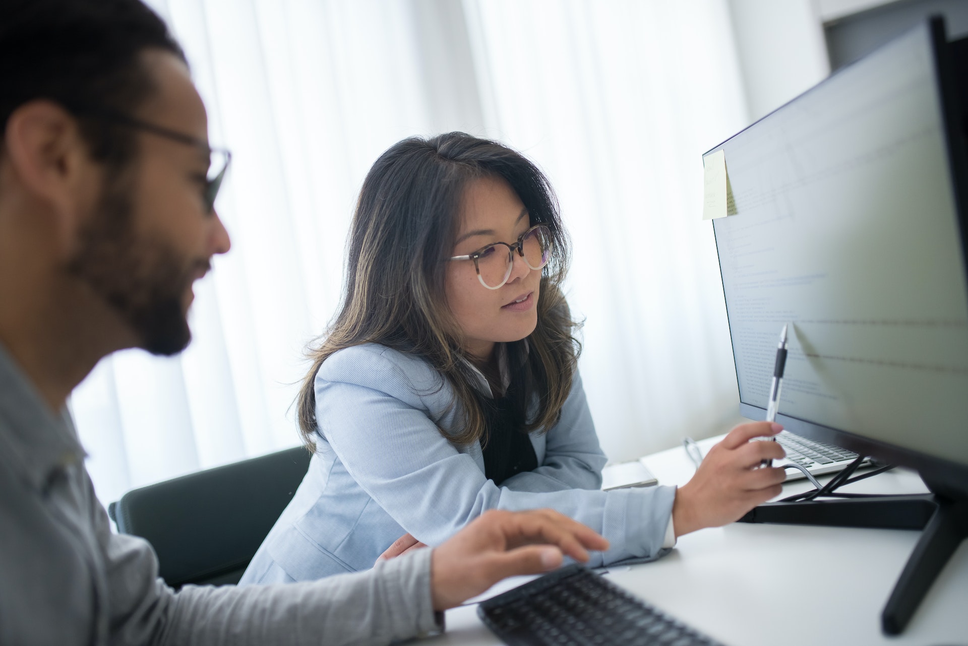 asian-woman-man-computer Asian woman reviewing performance management cycle with colleague
