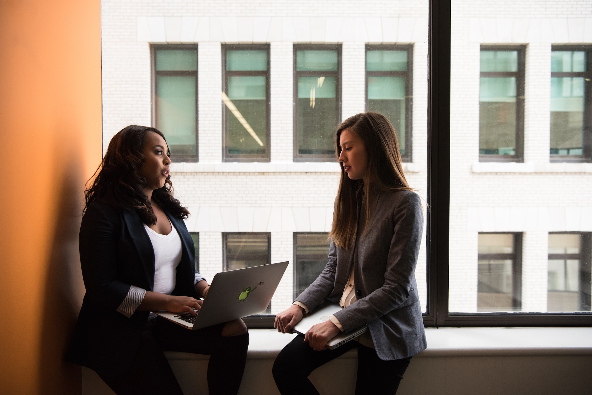 women-peer-feedback Black woman giving peer feedback to white woman colleague