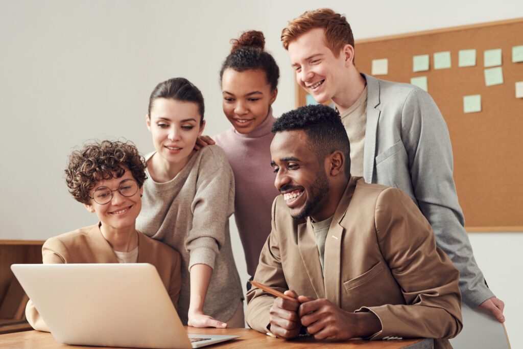 Diverse and inclusive group of employees looking at mid-year review criteria on laptop