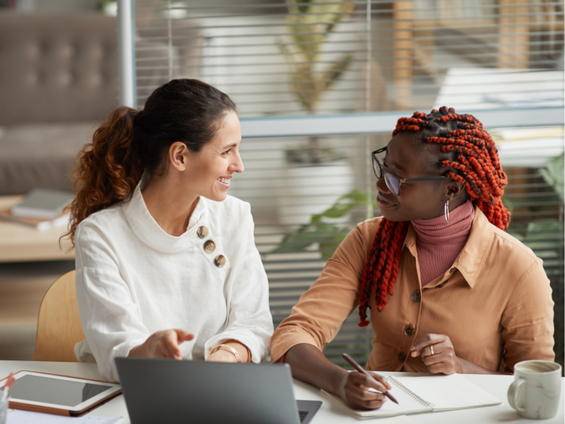 white-woman-black-woman-desk White woman and Black woman colleagues doing mid-year-review