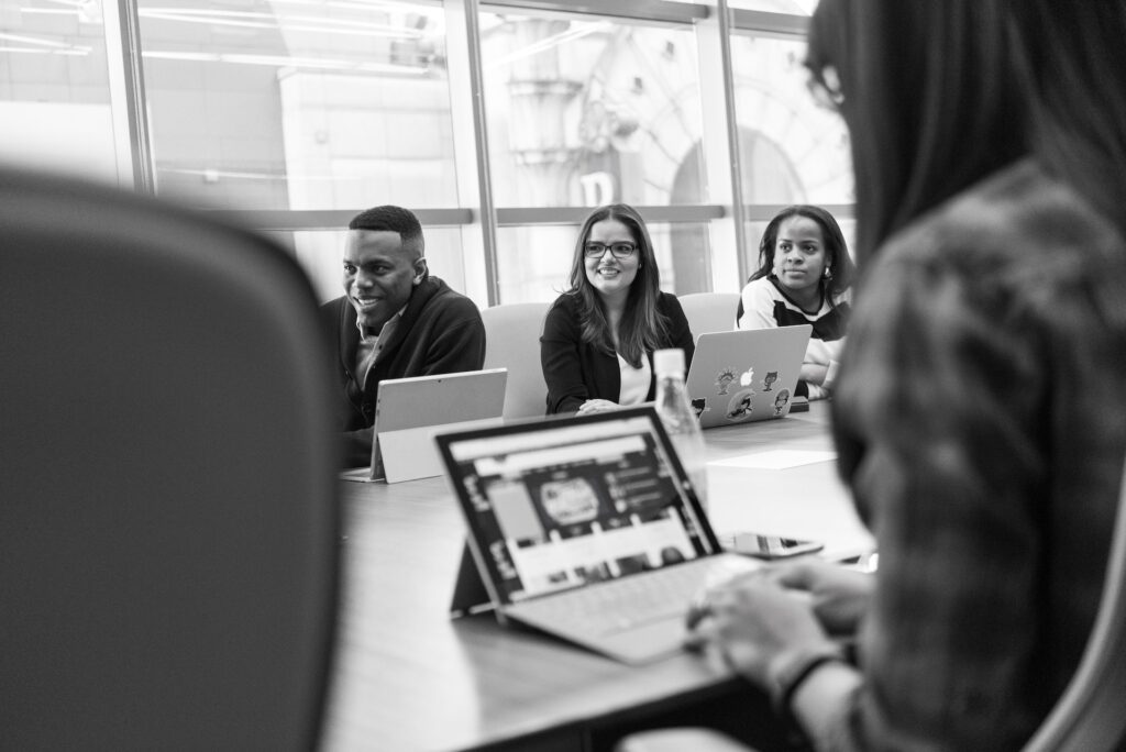Black and white image of colleagues happily meeting in office to discuss surveys and questionnaires