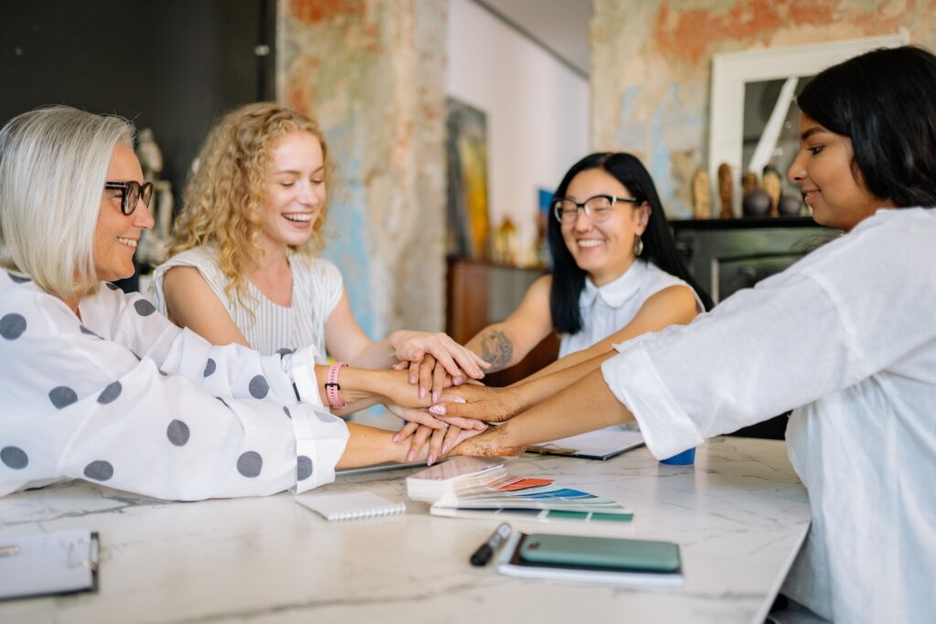 Multigenerational workforce women putting hands together in huddle
