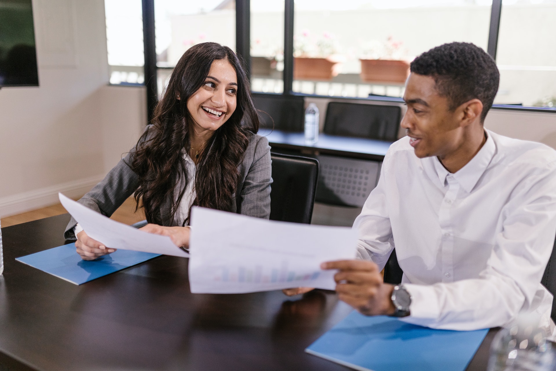 woman-man-desk-papers Woman of colour and Blak man giving each other workplace feedback