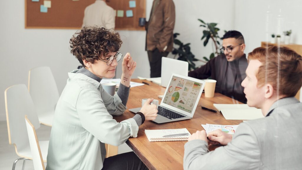 Inclusive group of employees meeting at a desk to discuss employee listening