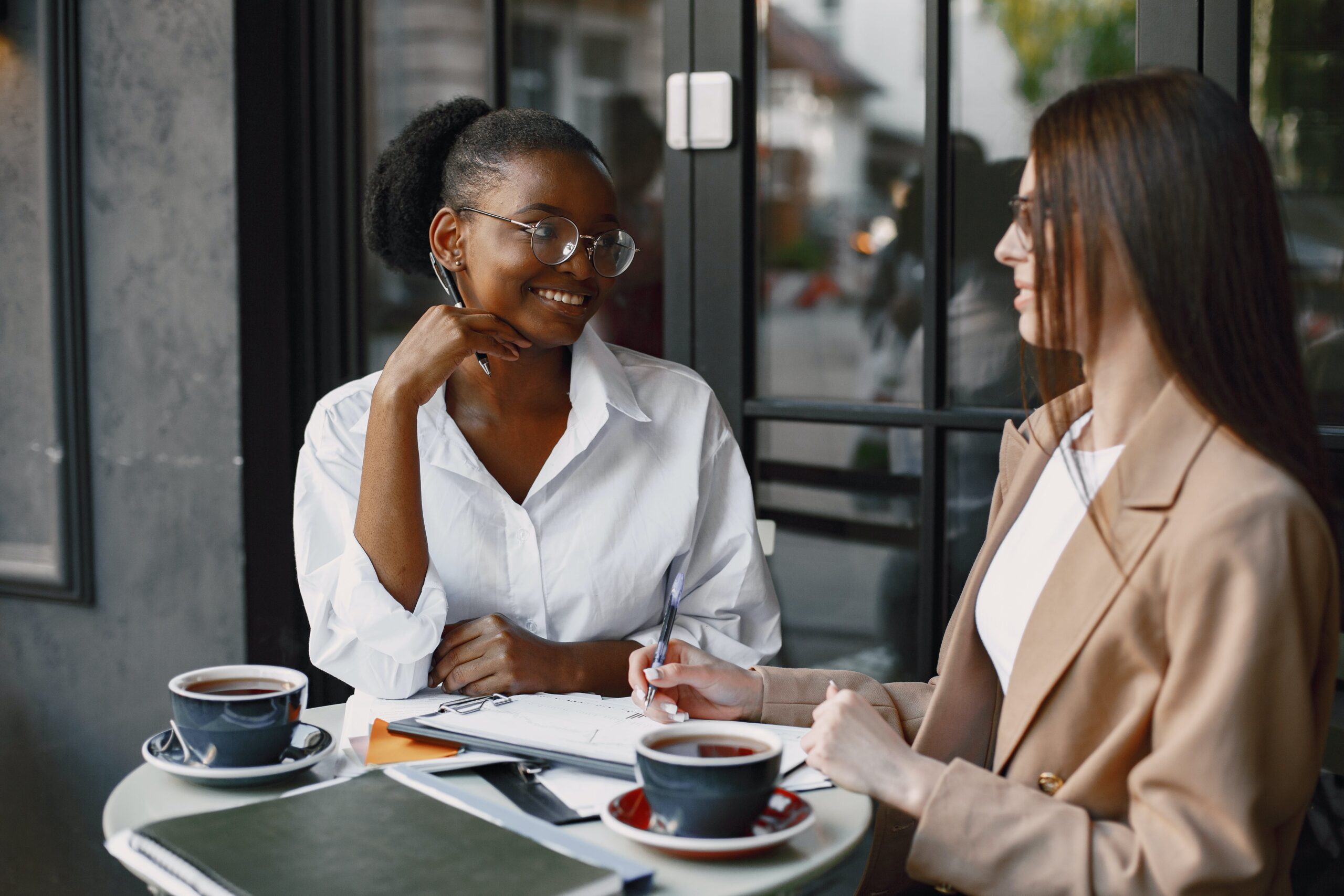women-talking-while-taking-notes-on-the-coffee-table HR professionals discussing employee engagement