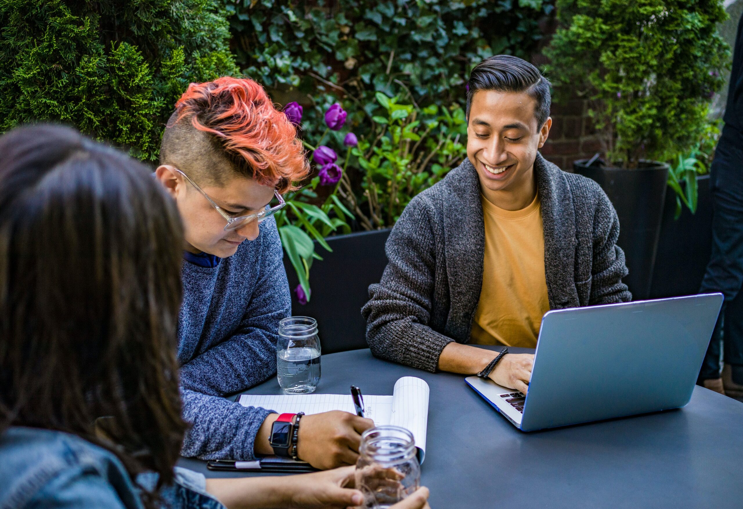 man-in-orange-crew-neck-shirt-using-laptop-beside-two-people HR professionals having a meeting to discuss the employee development and training
