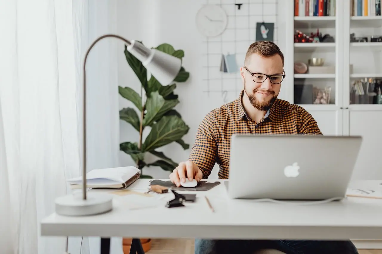 man-wearing-checkers-shirt-sitting-at-desk-working-from-laptop A manager filling out a 360 degree review