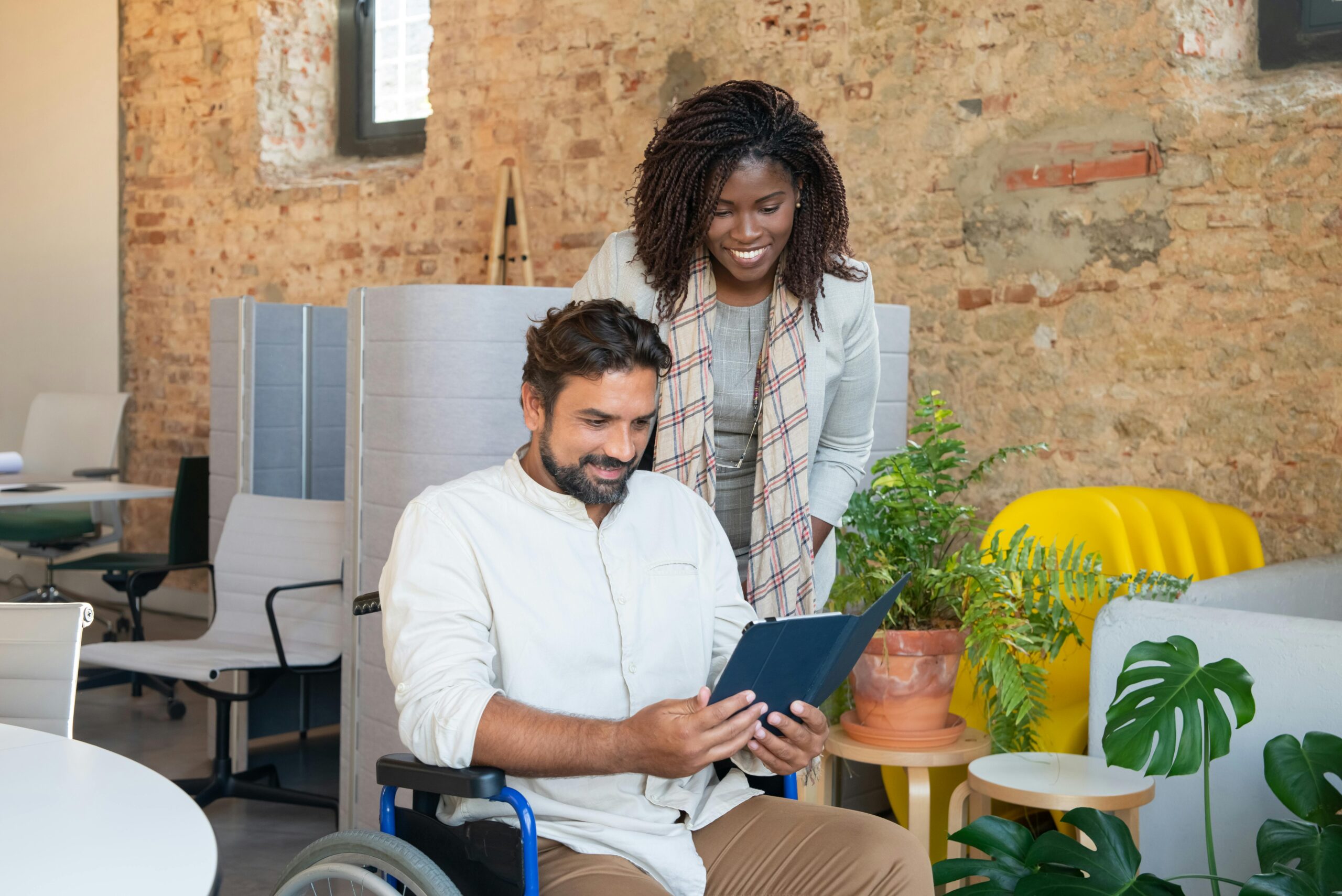 a-woman-in-plaid-scarf-standing-beside-the-man-sitting-on-wheelchair A woman and a man in a wheelchair discussing HR tactics to implement in 2024