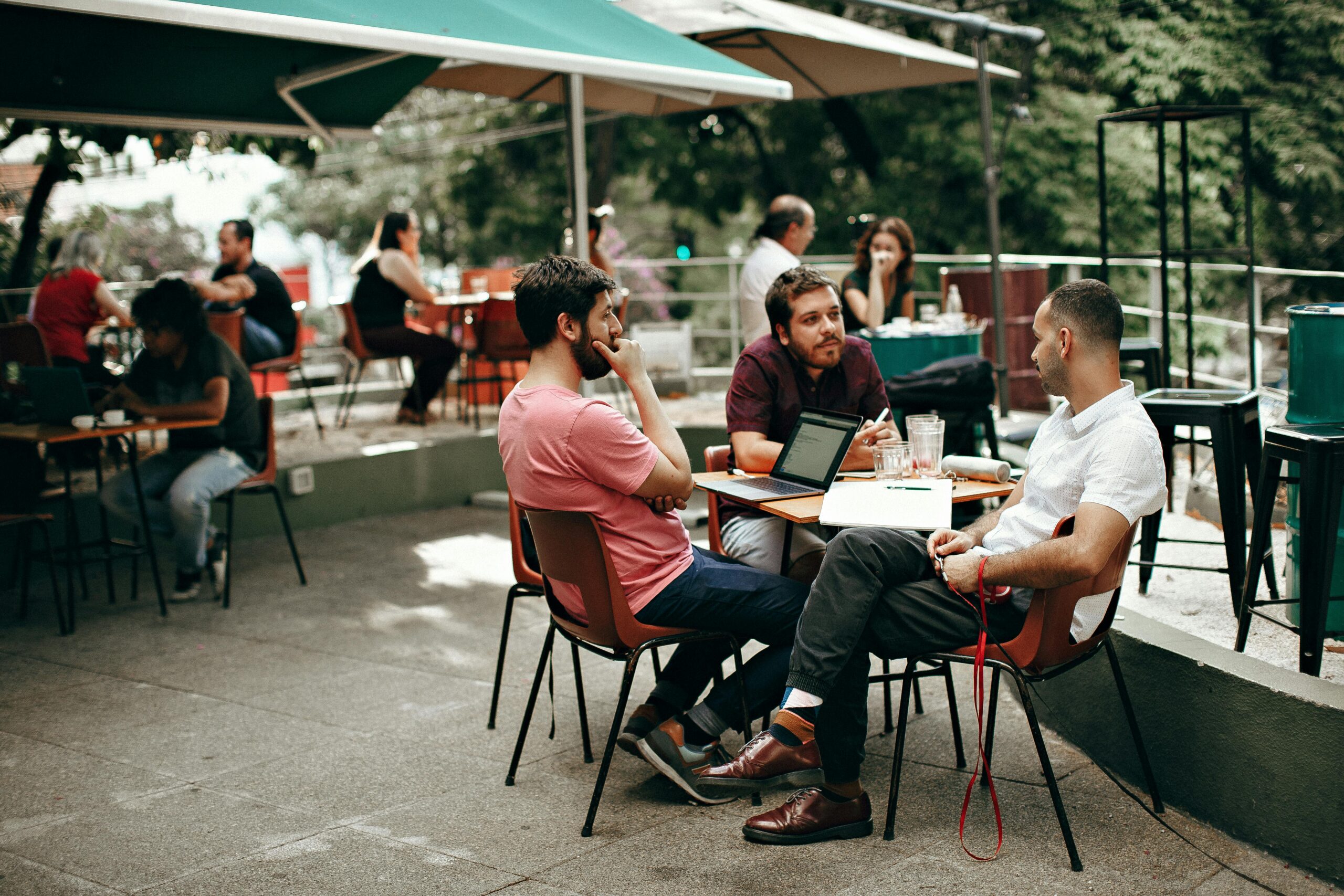 colleagues-sitting-outside-at-table Three coworkers bonding during an outdoor meeting