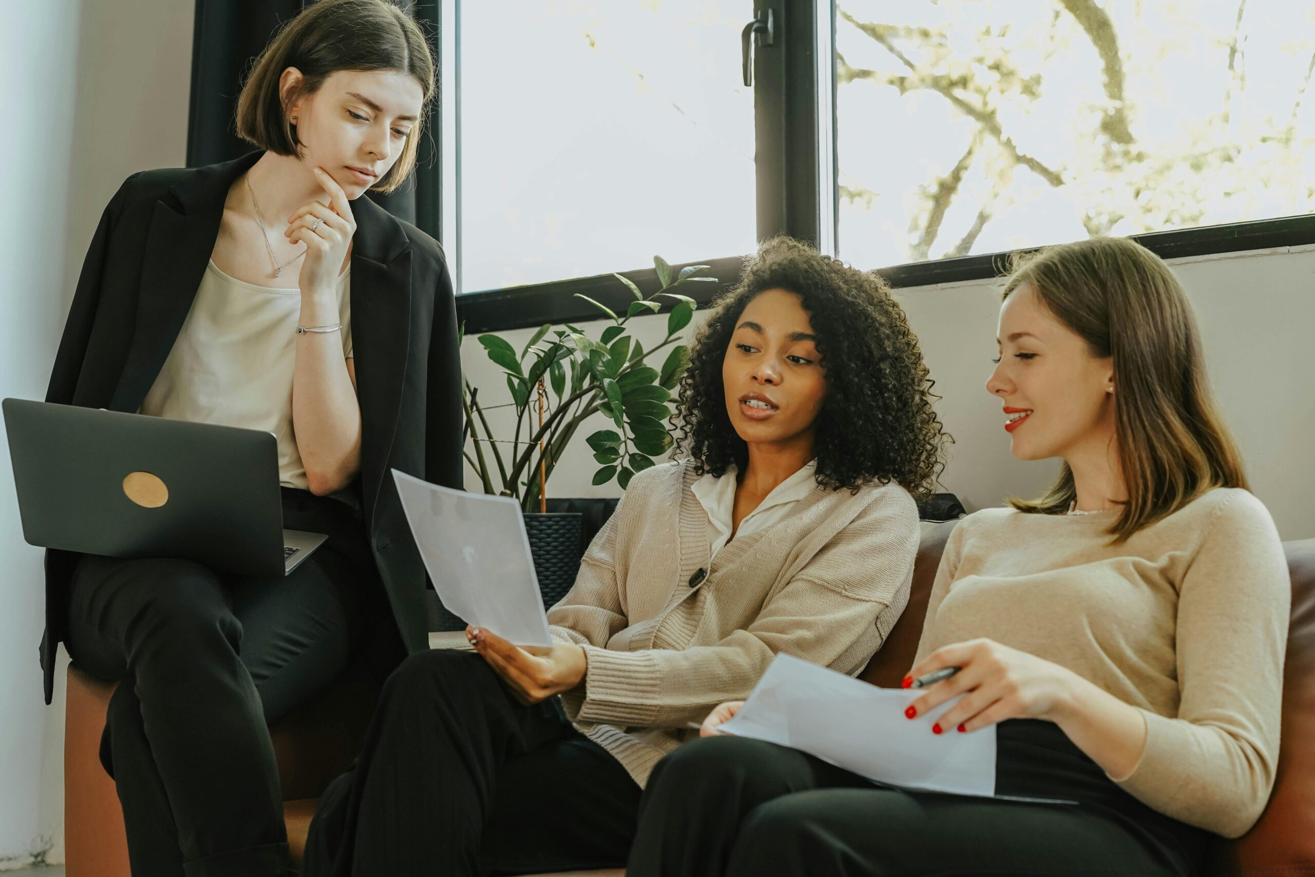 women-sitting-on-a-sofa-while-talking-business Three women are having a meeting